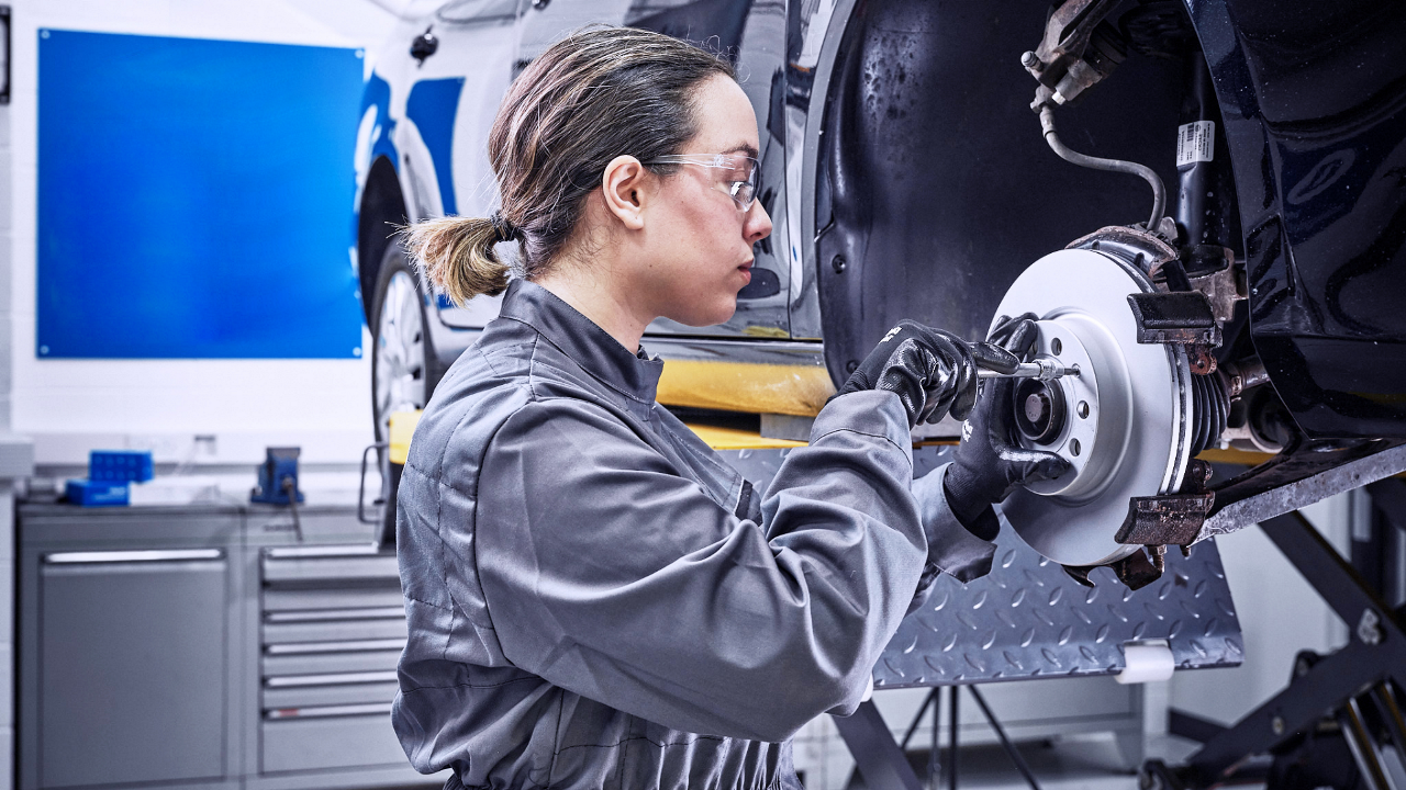 Delphi Expert replacing the front disks and brake pads of a raised vehicle.